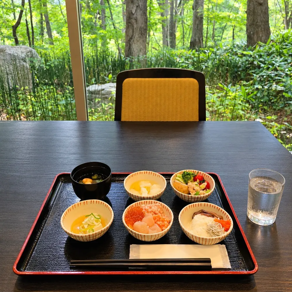 木々の緑が見える窓際の席に置かれた朝食のお盆